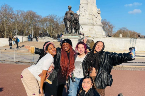 group of students pose in front of monument in london